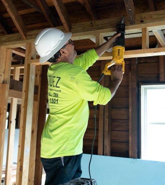 worker using electric saw on building frame